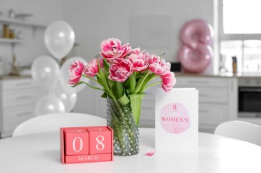Küp takvim, laleler ve tebrik kartı. Mutfaktaki yemek masasında mutlu kadınlar günü mesajı.