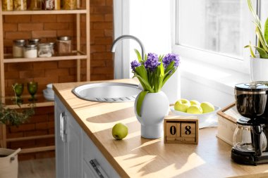 Çiçekli vazo, taze elmalar ve mutfak tezgahında 8 Mart tarihli küp takvimi. Uluslararası Kadınlar Günü kutlamaları