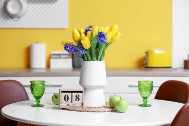 Küp takvimi, çiçekler, taze elma ve bardaklar yemek masasında. Uluslararası Kadınlar Günü kutlamaları