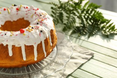 Lezzetli Paskalya pastası ve ahşap masanın üzerinde yeşil bir dal, yakın plan.