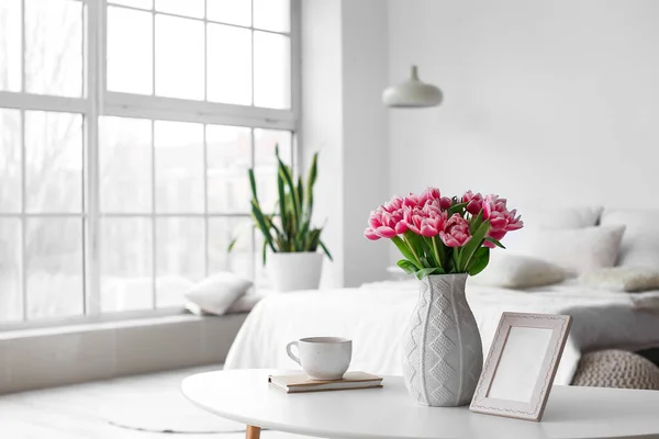 チューリップと花瓶 寝室のインテリアのテーブルの上のフォトフレームとカップ — ストック写真