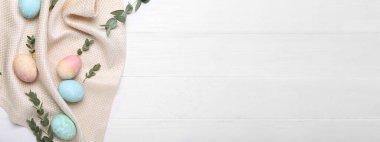 Okaliptüs dallarıyla boyanmış Paskalya yumurtaları ve beyaz ahşap zemin üzerinde yazı için yeri olan peçete.