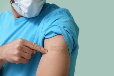 Arkaplanda aşıdan sonra maske takan genç adam, yakın plan