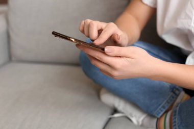 Evde cep telefonu kullanan genç ve güzel bir kadın.