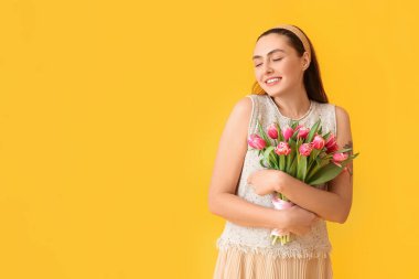 Sarı arka planda bir buket lale ile gülümseyen genç kadın. Uluslararası Kadınlar Günü