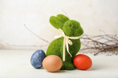 Güzel Paskalya tavşanı ve açık arkaplanda boyanmış yumurtalar.