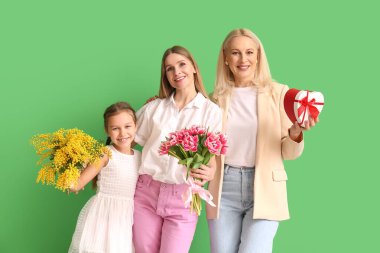 Küçük kızı, annesi ve yeşil arka planda hediyeleri olan genç bir kadın. Uluslararası Kadınlar Günü