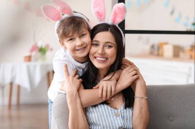 Küçük çocuk ve annesi tavşan kulaklı. Paskalya günü evde sarılıyorlar.