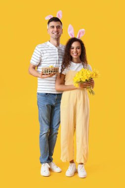 Sarı arka planda Paskalya yumurtaları ve laleleri olan mutlu çift.
