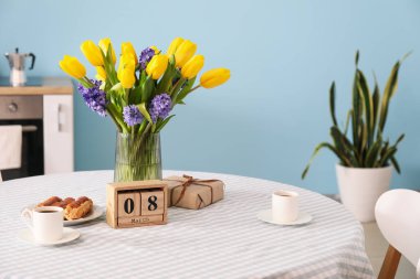 Küp takvimi, çiçekler, hediye kutusu ve fincanlar yemek masasında. Uluslararası Kadınlar Günü kutlamaları