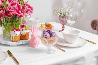 Şık yemek takımı, servis edilen masada Paskalya kekleri ve yumurtalar.