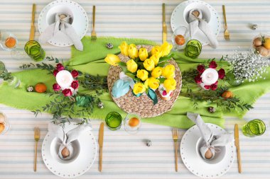 Paskalya kutlaması için masasında güzel çiçekler ve mumlar olan şenlikli bir ortam.