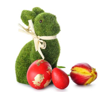 Beyaz arka planda boyalı yumurtaları ve çiçekleri olan şirin Paskalya tavşanı.