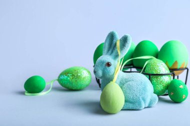 Tatlı Paskalya tavşanı ve gri arka planda boyanmış yumurtalar.