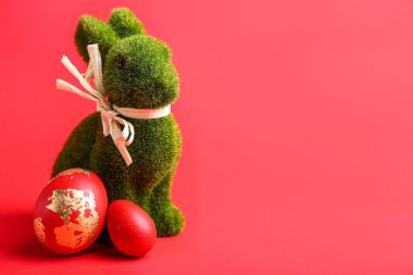 Tatlı Paskalya tavşanı ve kırmızı arka planda boyanmış yumurtalar.