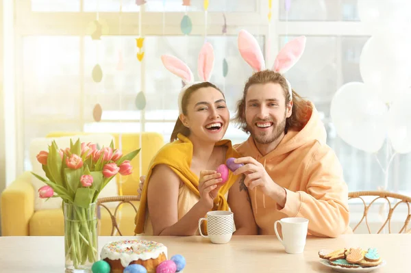 Gelukkig Paar Konijnenoren Kraken Paaseieren Aan Tafel — Stockfoto