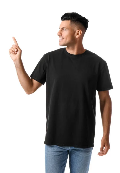 白い背景に何かを指すスタイリッシュなTシャツのハンサムな若い男 — ストック写真