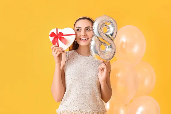 Sarı Arka Planda Hediyeleri Balonları Olan Mutlu Genç Bir Kadın — Stok fotoğraf