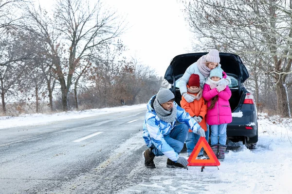 冬の雪の日に壊れた車の近くの両親と子供たち — ストック写真