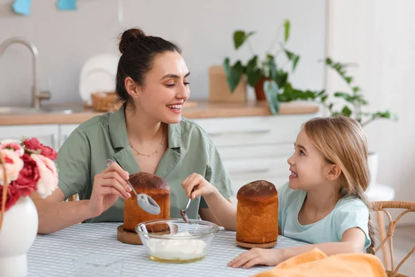 小女孩和她的母亲在厨房里给复活节蛋糕上色 — 图库照片