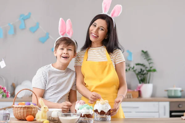 小さな男の子と彼の母親は台所でイースターケーキを飾る — ストック写真