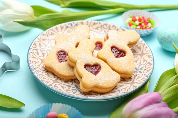 Teller Mit Leckeren Osterkeksen Und Tulpenblumen Auf Blauem Hintergrund — Stockfoto