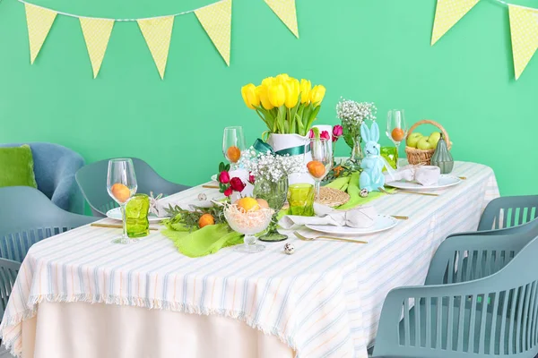 カラーウォール近くのイースターお祝いのためのスタイリッシュなお祝いテーブル設定 — ストック写真