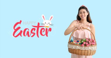 Paskalya tebrik kartı, mavi arka planda sepet tutan güzel Asyalı bir kadın.