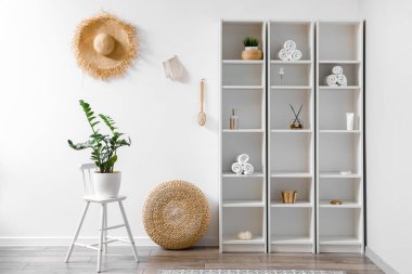 Raf ünitesi ve rattan pouf olan hafif banyonun içi.