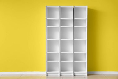 Sarı duvarın yanındaki boş raf ünitesi.