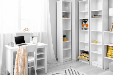 Modern işyeri ve büyük raf ünitesiyle aydınlık oturma odasının içinde.