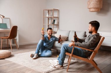 Bira şişeleri olan erkek arkadaşlar evde eğleniyorlar.