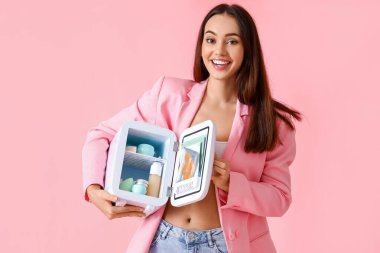 Küçük buzdolabı ve renkli kozmetik ürünleri olan güzel genç bir kadın.