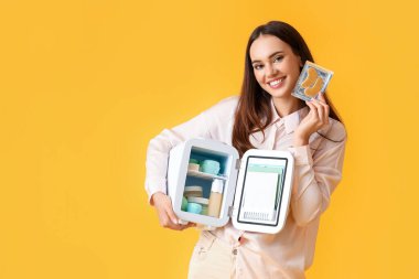 Küçük buzdolabı ve renkli kozmetik ürünleri olan güzel genç bir kadın.