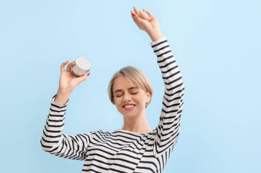 Modern kablosuz hoparlör tutan ve mavi arka planda dans eden bir kadın.