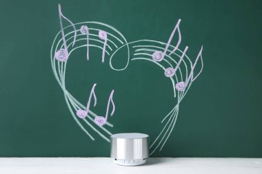 Kablosuz taşınabilir hoparlör ve yeşil arkaplan üzerine müzik notaları çizimi