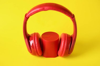 Sarı arka planda kablosuz taşınabilir hoparlör ve kulaklık.