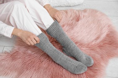 Yumuşak halıya sıcak çorap giymiş bir kadın. Isınma mevsimi kavramı