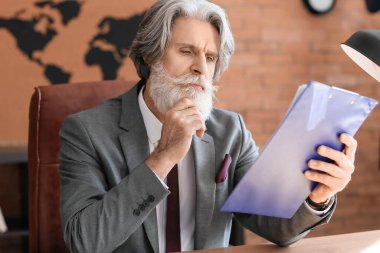 Ofiste çalışan olgun sakallı bir iş adamı.