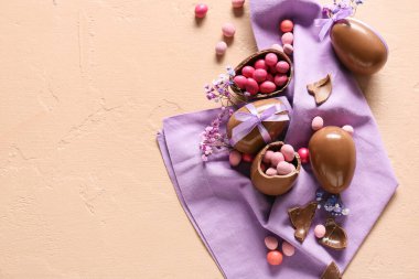 Çikolatalı Paskalya yumurtaları, şekerler ve renkli arka planda çigila çiçekleri.