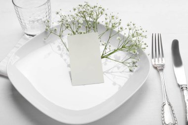 Boş kartlı masa ayarları ve beyaz ahşap arka planda çingene çiçekleri