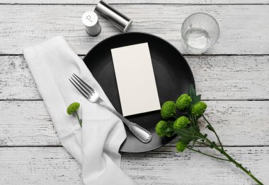 Boş kartlı şık masa ayarları ve hafif ahşap arka planda çiçekler