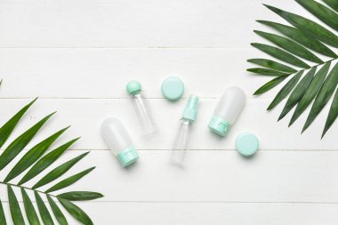 Boş seyahat şişeleri, kavanozlar ve ahşap arka planda palmiye yaprakları.