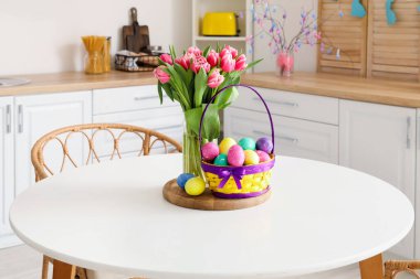 Paskalya yumurtaları, vazo ve laleler mutfakta yemek masasında.
