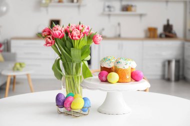 Mutfaktaki yemek masasında Paskalya pastaları, yumurtalar ve lalelerin yanında dur.