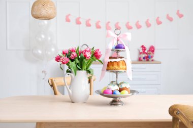 Mutfaktaki yemek masasında Paskalya pastaları, yumurtalar ve lalelerin yanında dur.