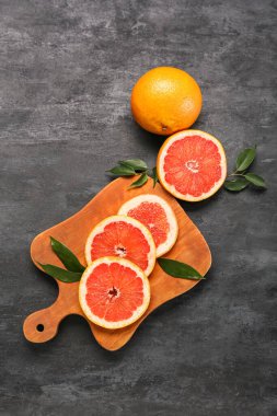 Koyu arkaplanda taze greyfurt dilimleri olan tahta