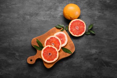 Koyu arkaplanda taze greyfurt dilimleri olan tahta