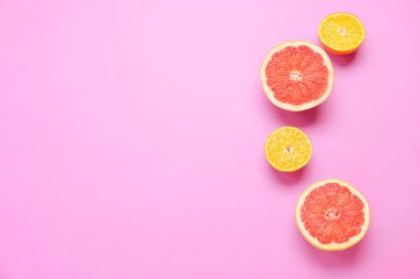 Pembe arka planda taze portakal ve greyfurt dilimleri.