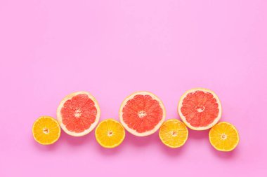 Pembe arka planda taze portakal ve greyfurt dilimleri.